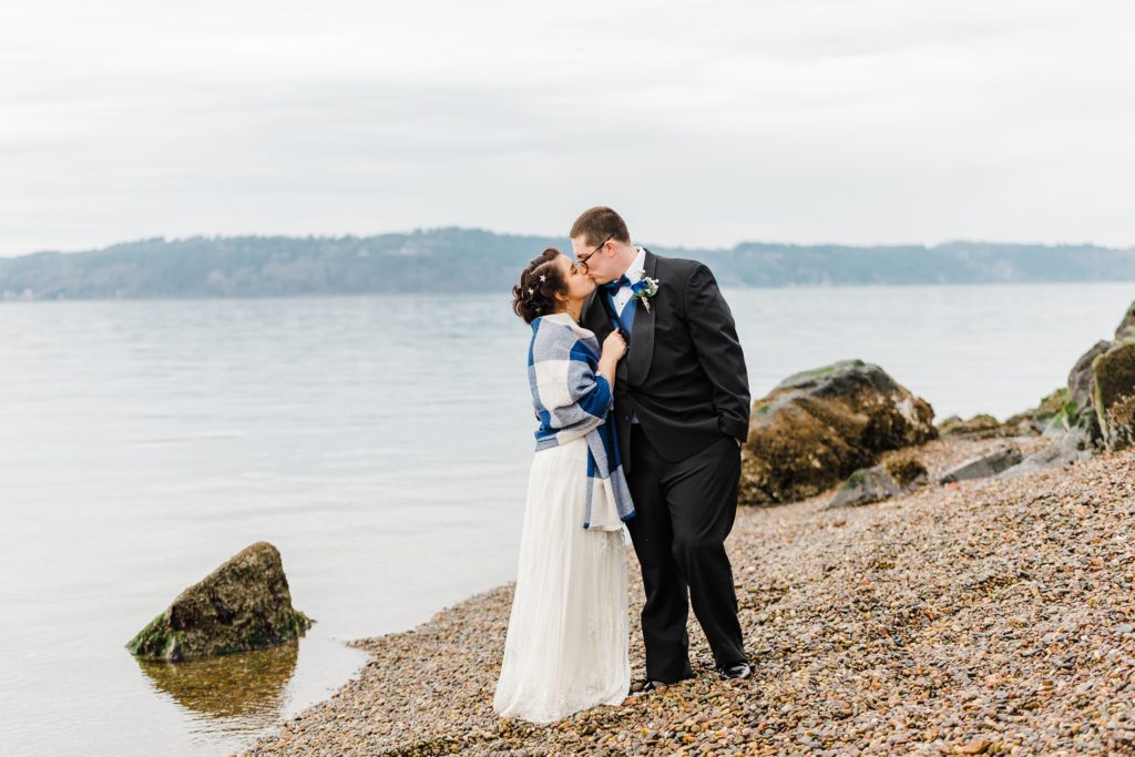 bride and groom kiss on the rocky beach