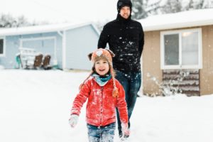 father and son walk through the snow laughing