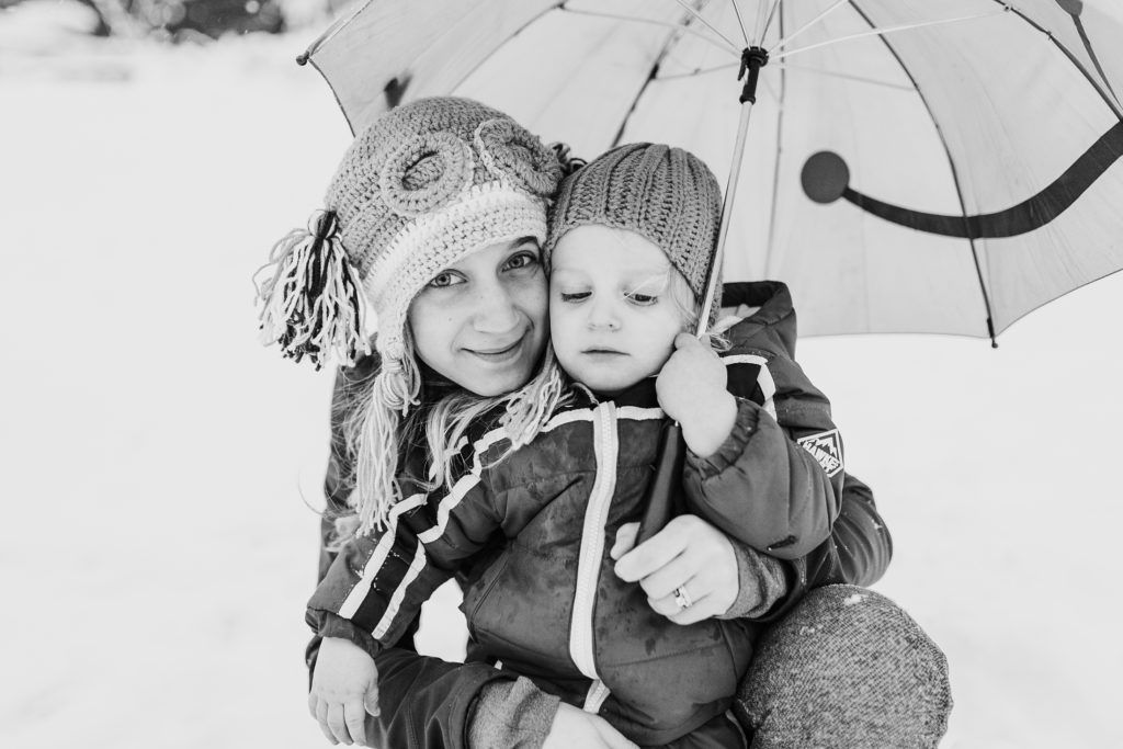 black and white mom and son under frog umbrella