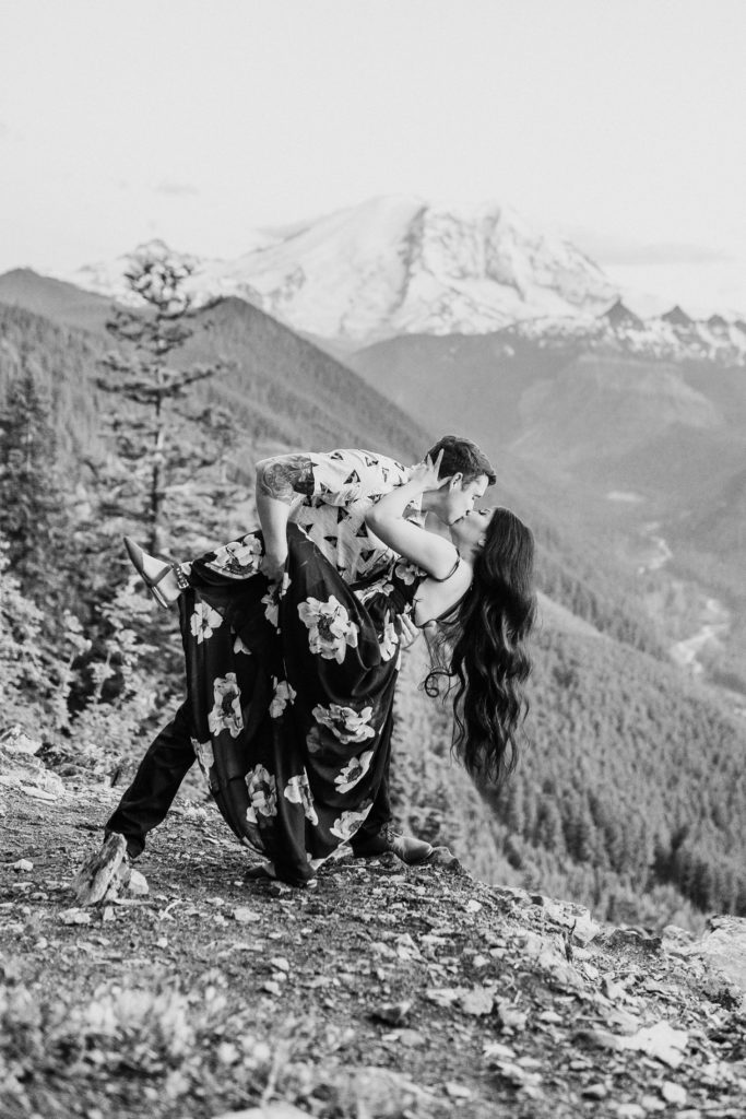 black and white man dips and kisses woman on mountain